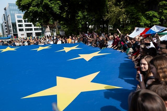 immagine di una manifestazione con persone che reggono una bandiera UE gigante