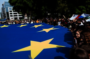 immagine di una manifestazione con persone che reggono una bandiera UE gigante